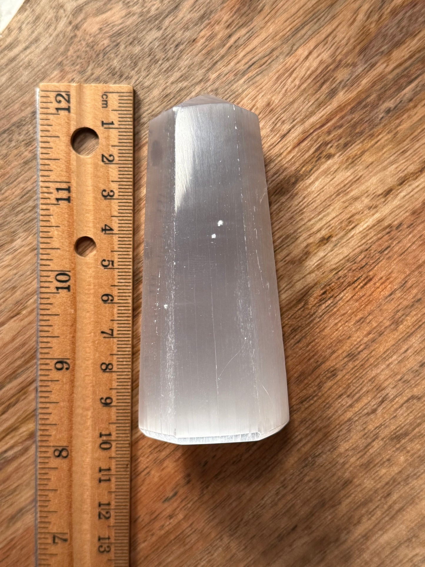 Clear crystal object next to a wooden ruler on a wooden surface