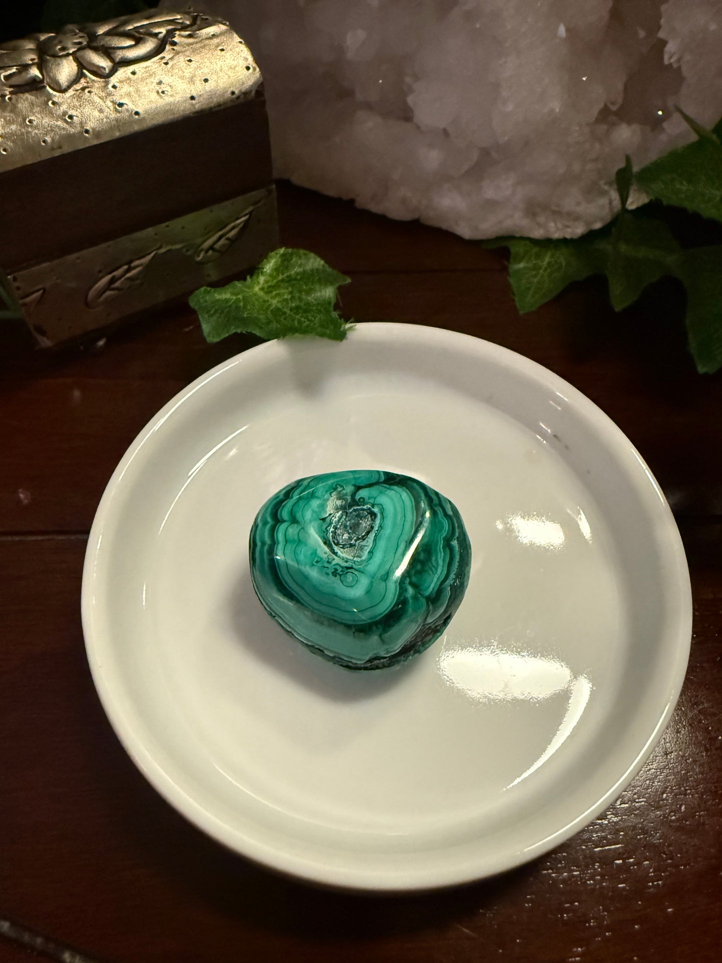 Malachite stone on a white dish with a wooden surface and decorative elements in the background