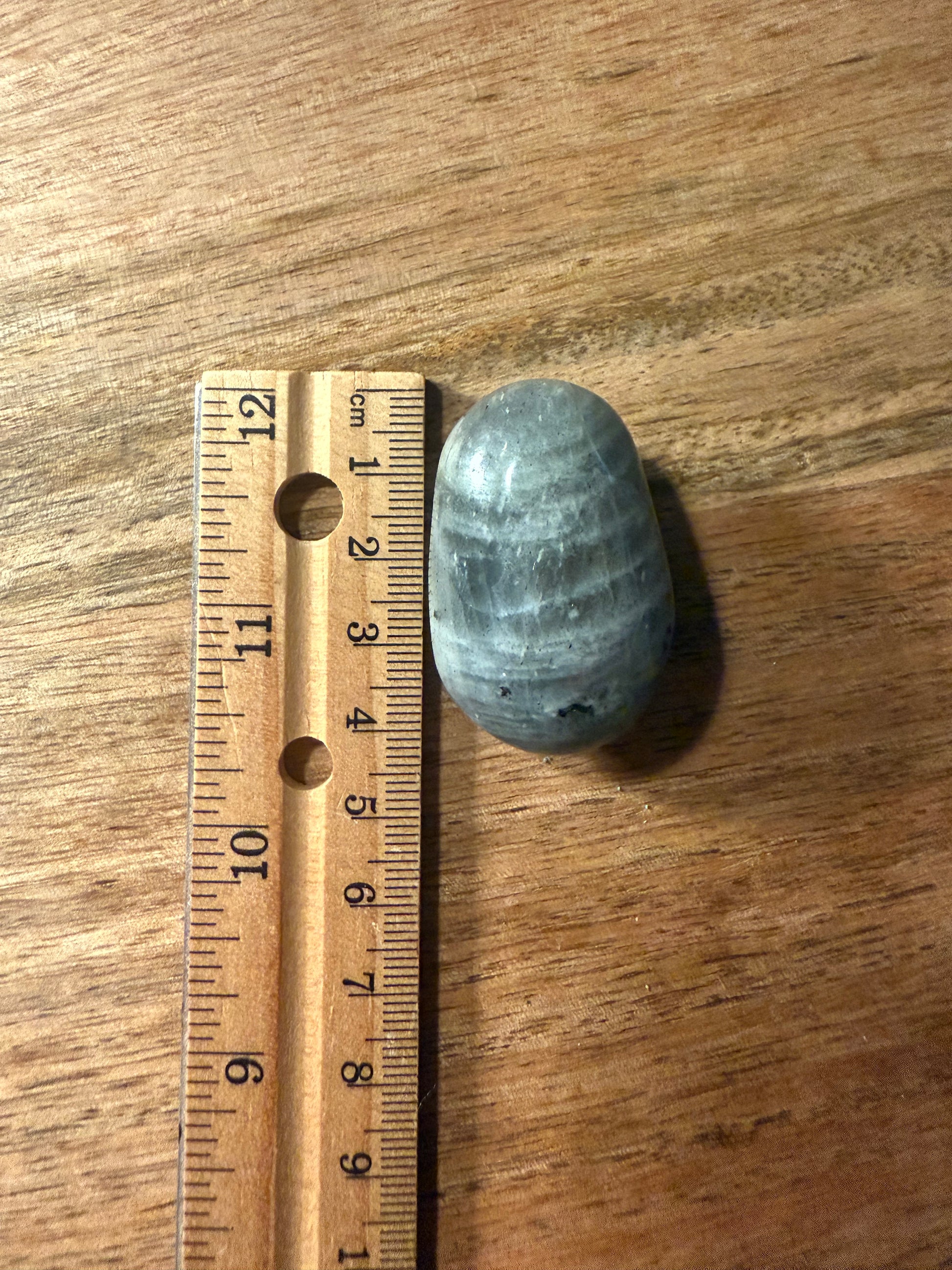 Ruler next to a blue stone on a wooden surface