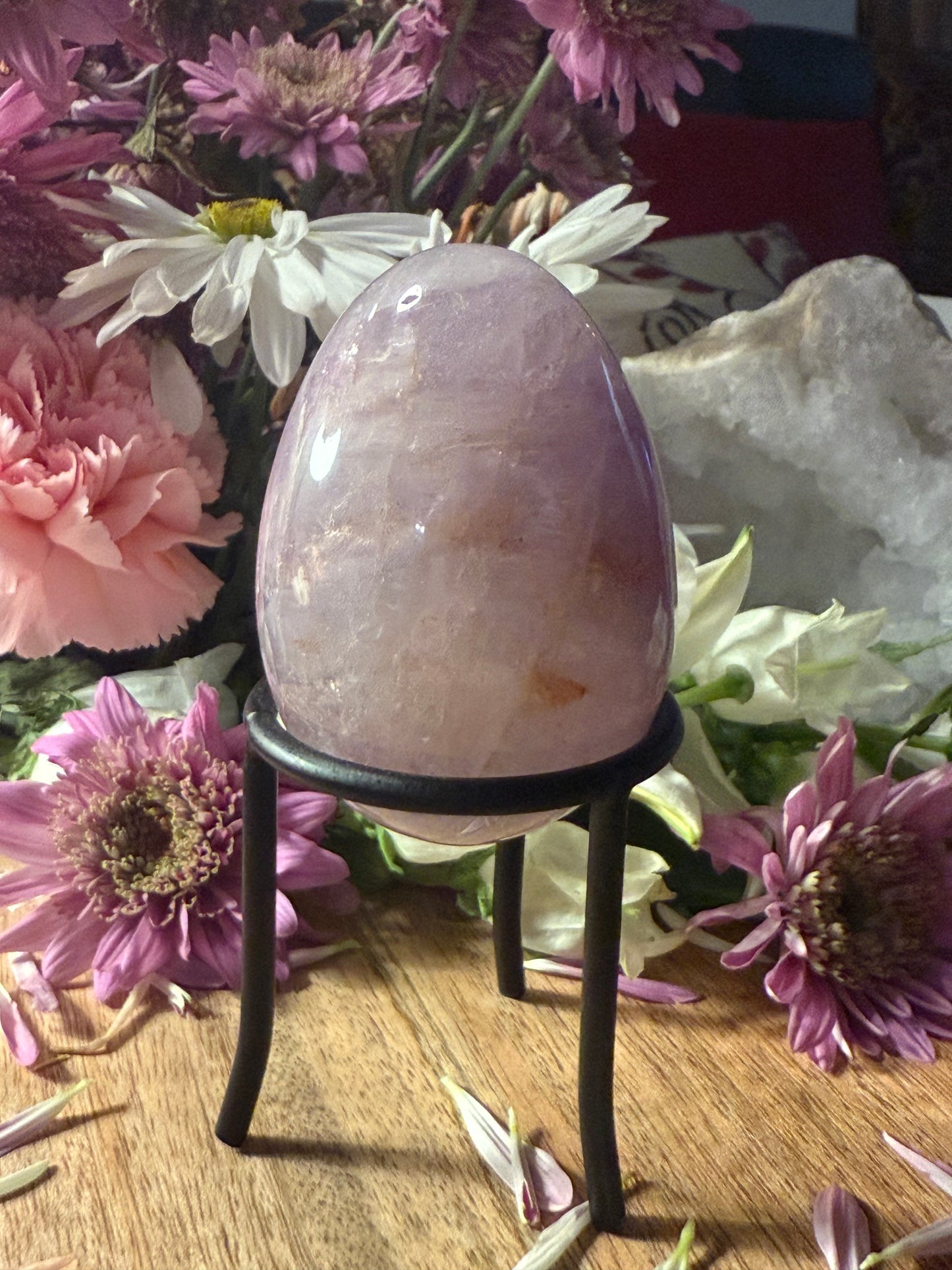 Crystal egg on a stand surrounded by flowers