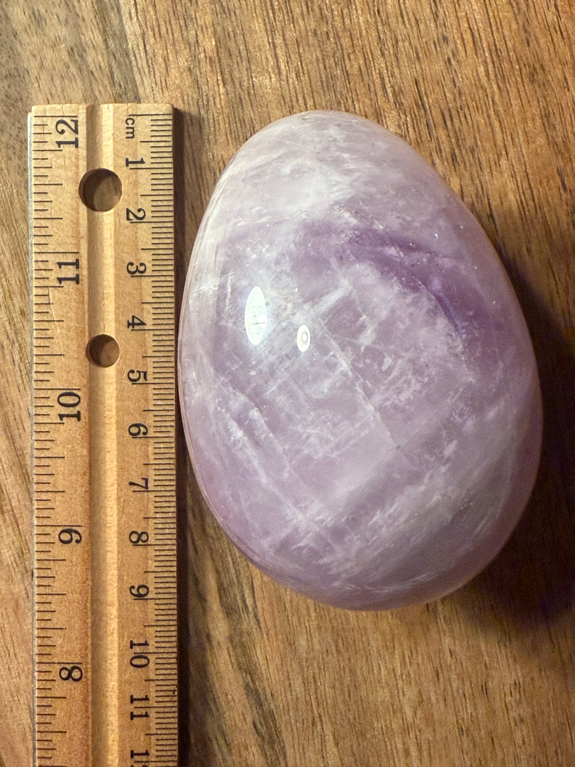 Amethyst crystal on a wooden surface with a ruler for scale.