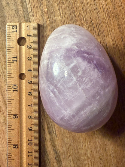 Amethyst crystal on a wooden surface with a ruler for scale.