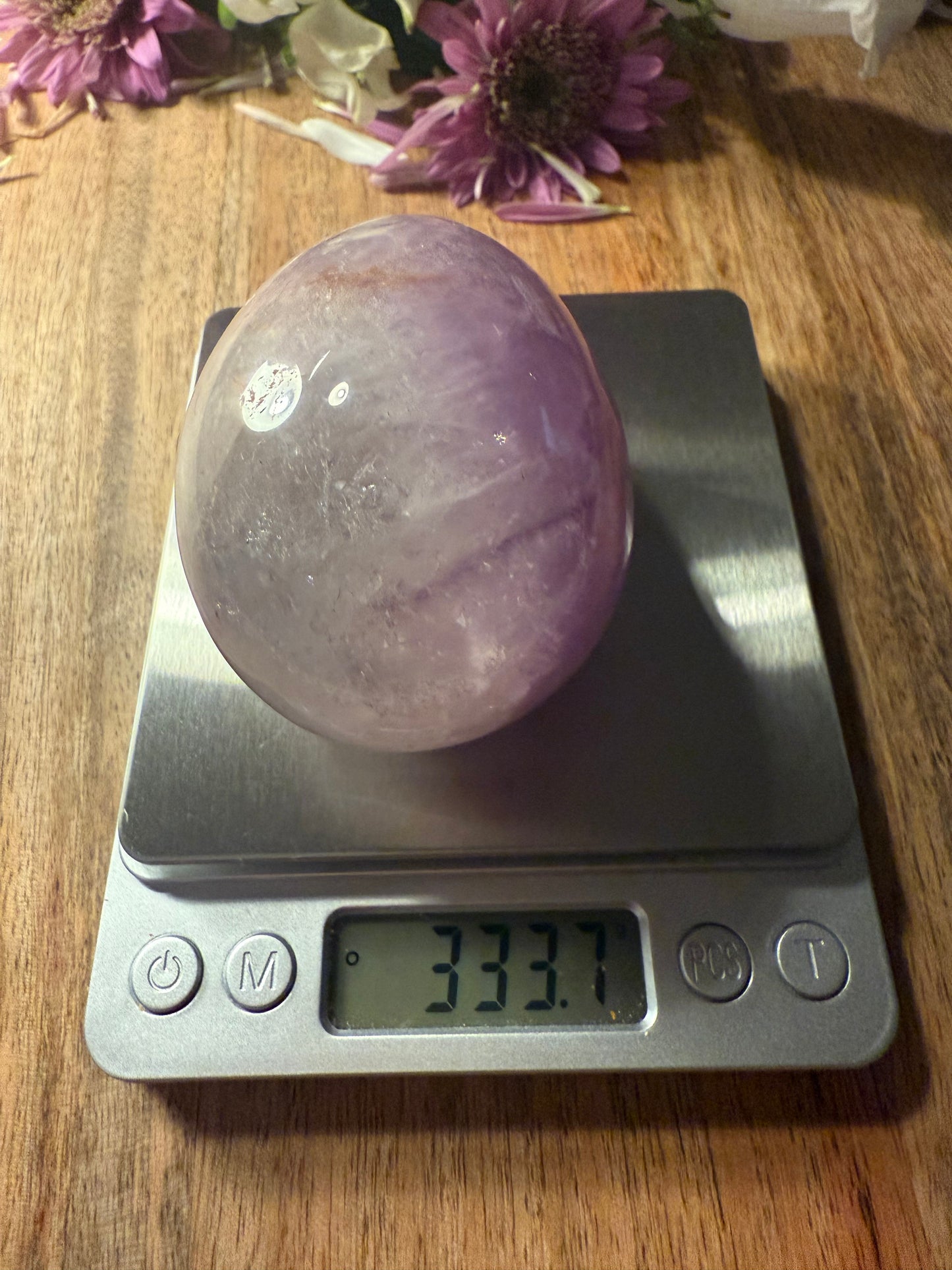 Purple crystal ball on a digital scale with flowers in the background