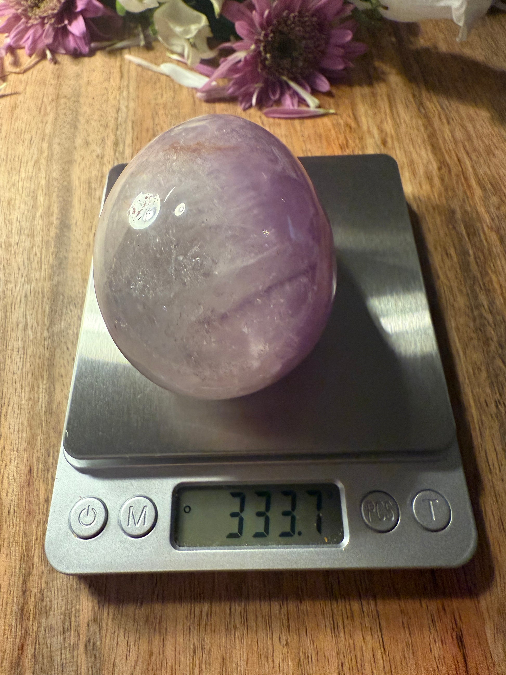 Purple crystal ball on a digital scale with flowers in the background