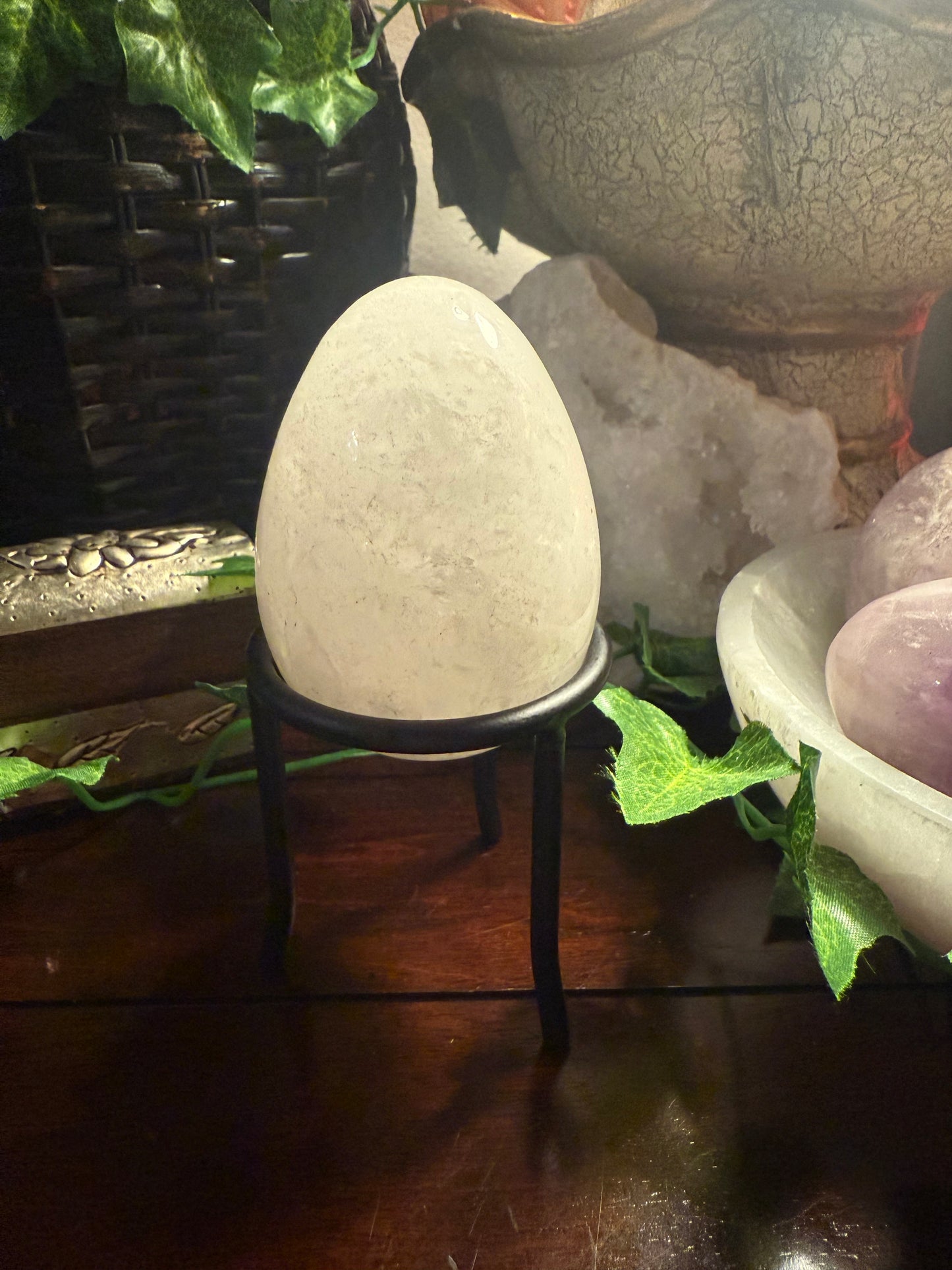 Decorative stone egg on a stand with plants and stones in the background