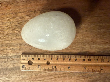 White stone on a wooden surface with a ruler for scale