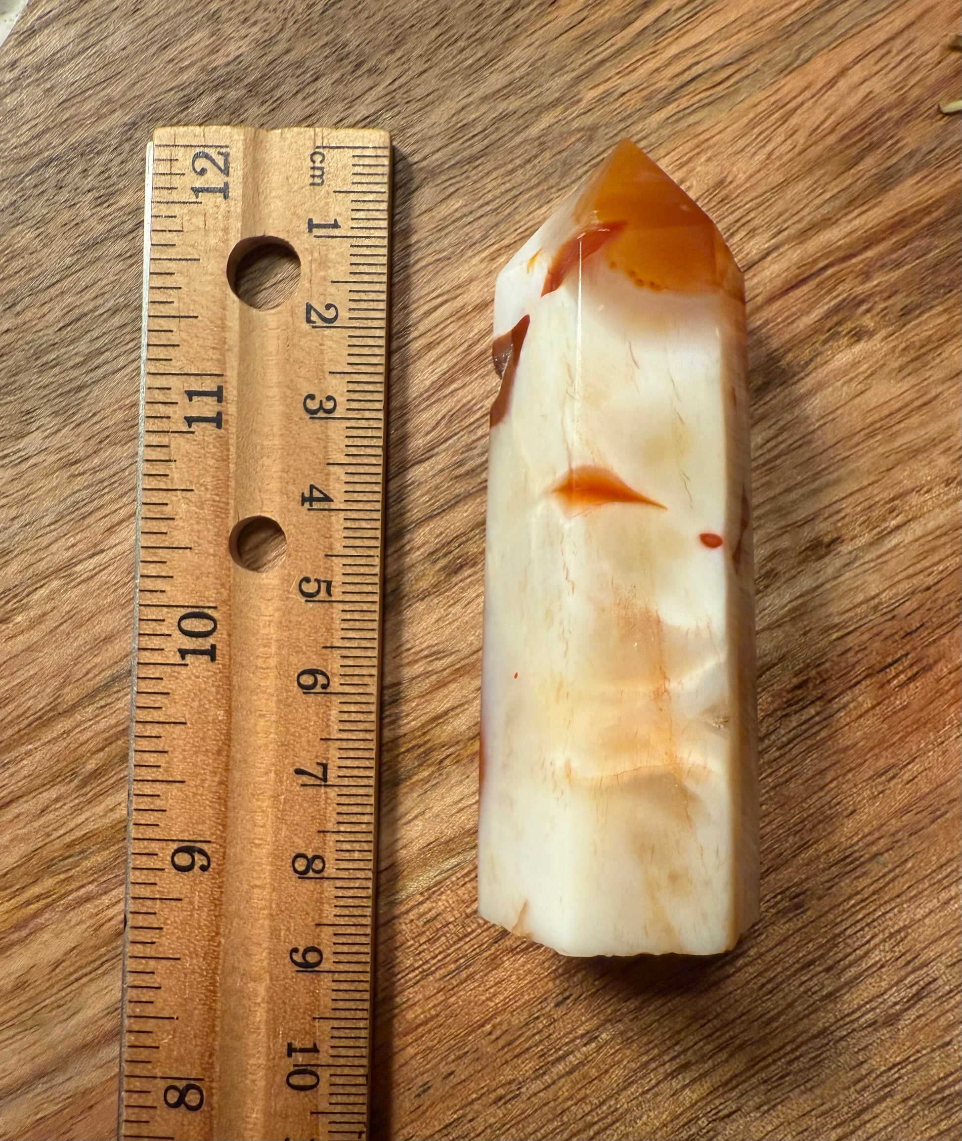 Carnelian Agate Crystal Point with a ruler for scale on a wooden surface