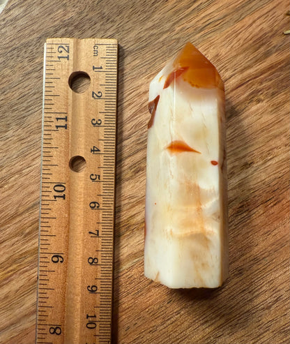Carnelian Agate Crystal Point with a ruler for scale on a wooden surface