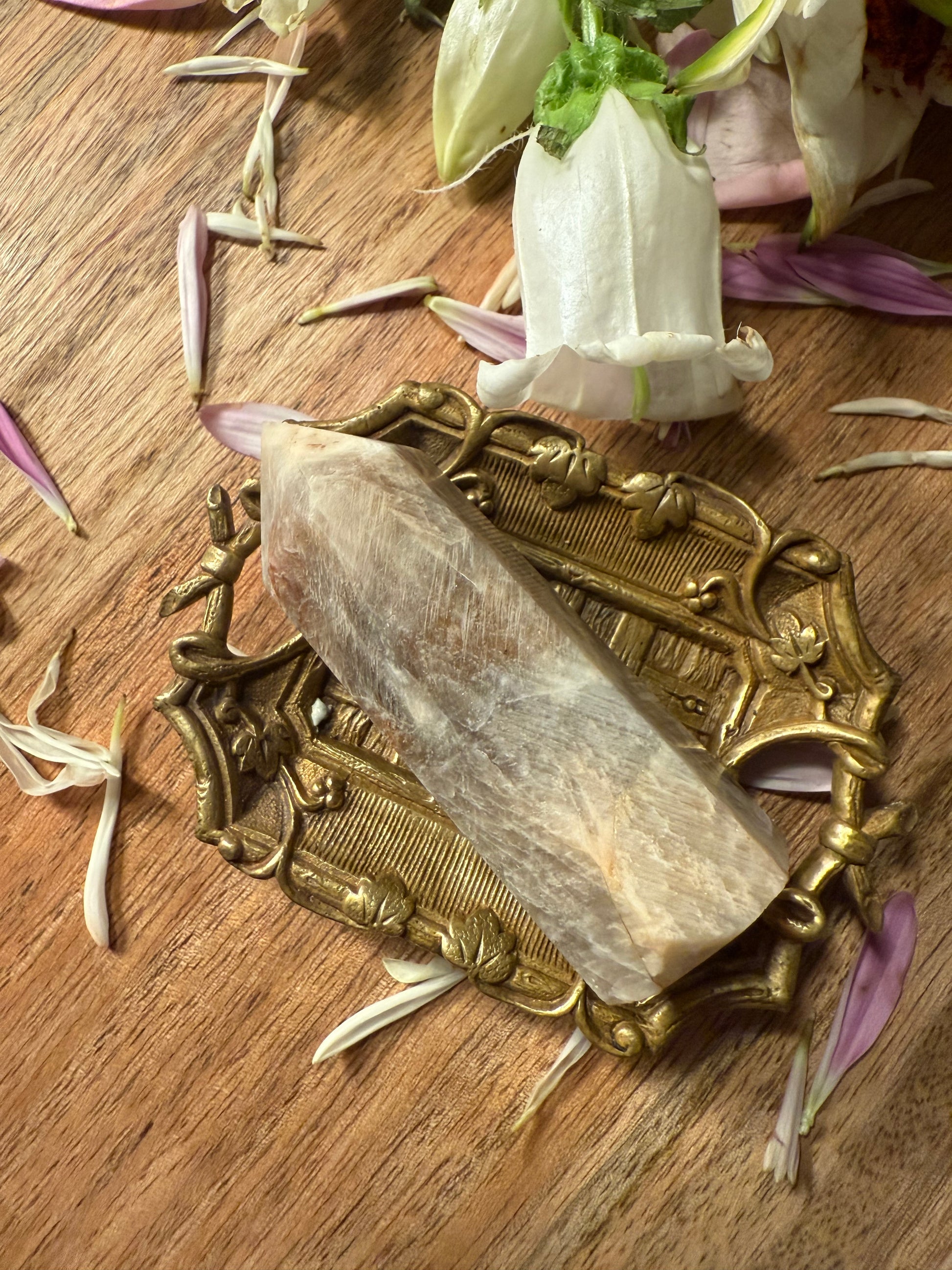 Decorative stone on a brass stand on a wooden surface with flowers.