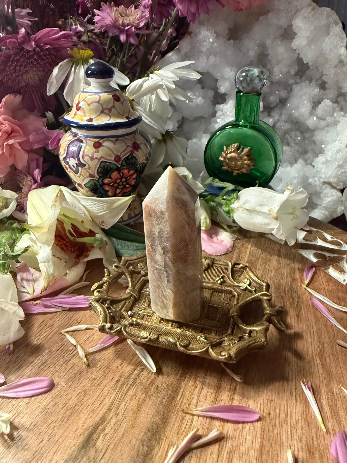 Decorative setup with a crystal on a stand, surrounded by flowers and decorative bottles.