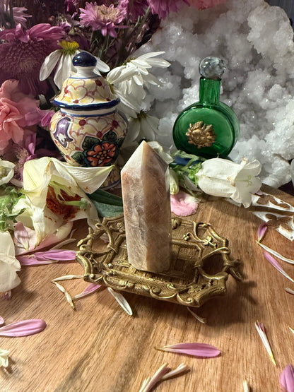 Decorative setup with a crystal on a stand, surrounded by flowers and decorative bottles.