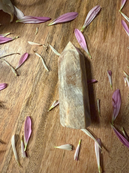 Stone tool on a wooden surface with scattered flower petals