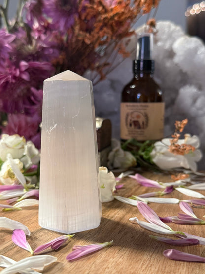Selenite tower with a bottle of essential oil on a table with flowers