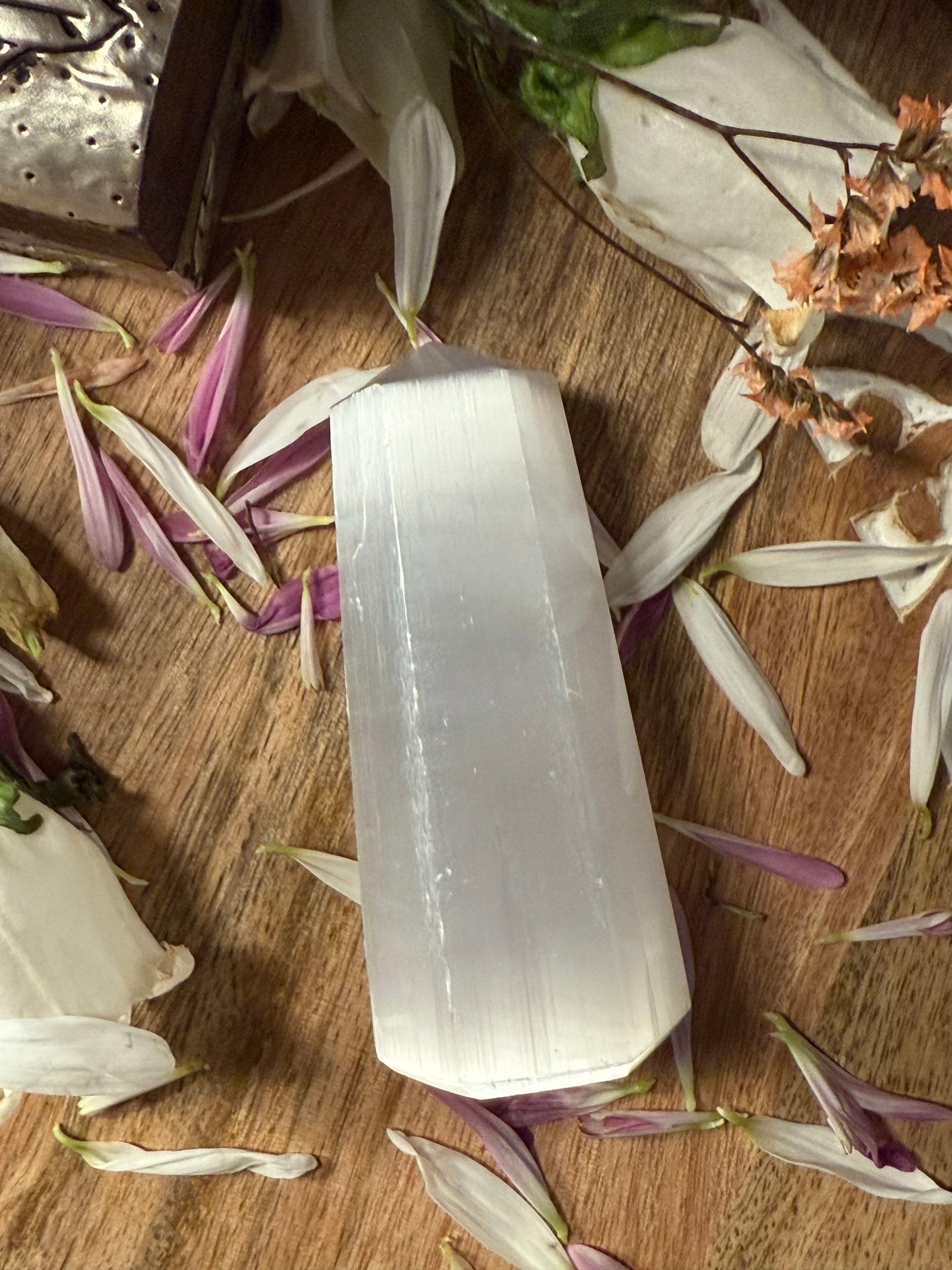 Selenite crystal on a wooden surface with dried flowers