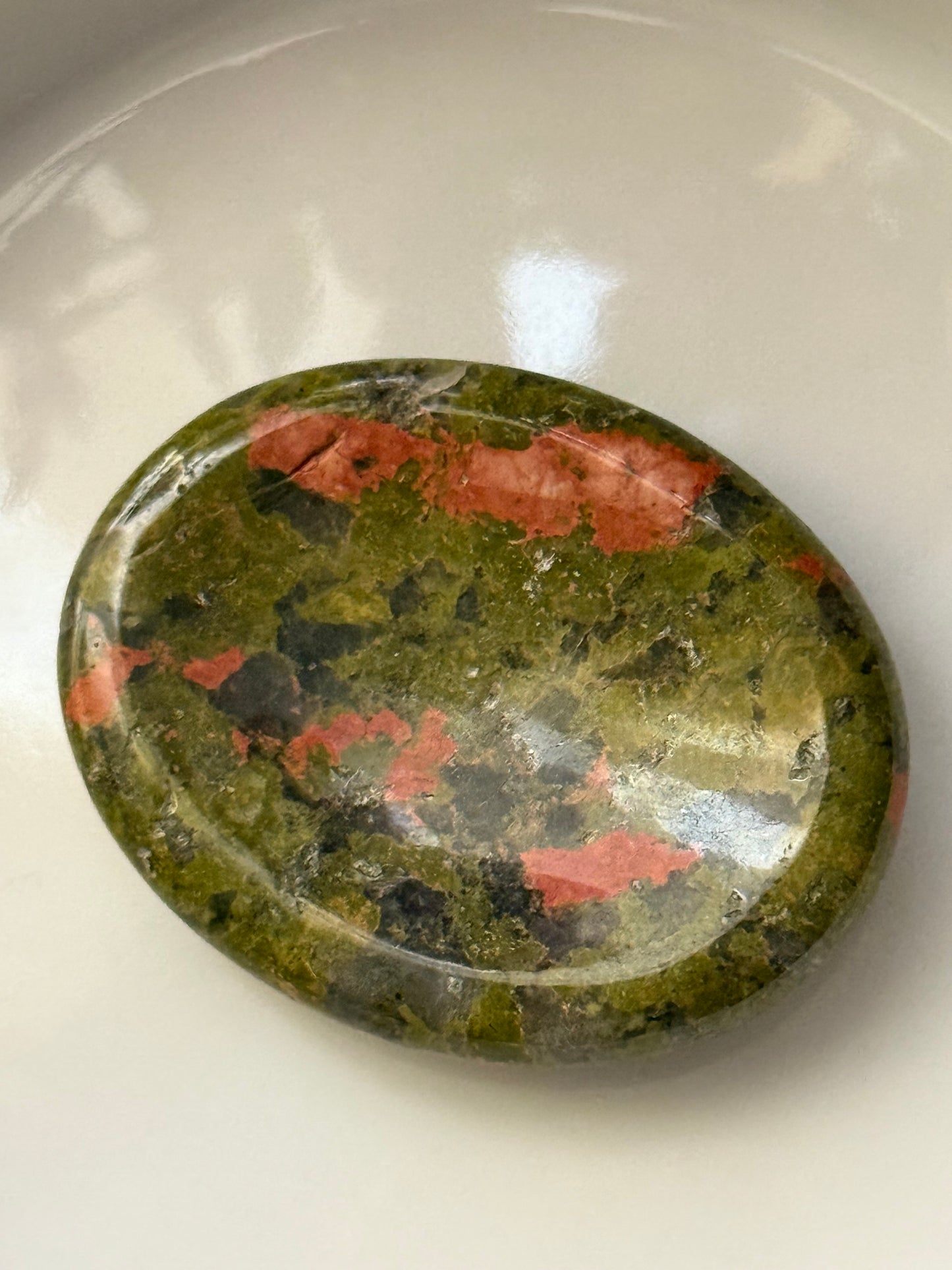 Polished stone with green, red, and black patterns on a white background