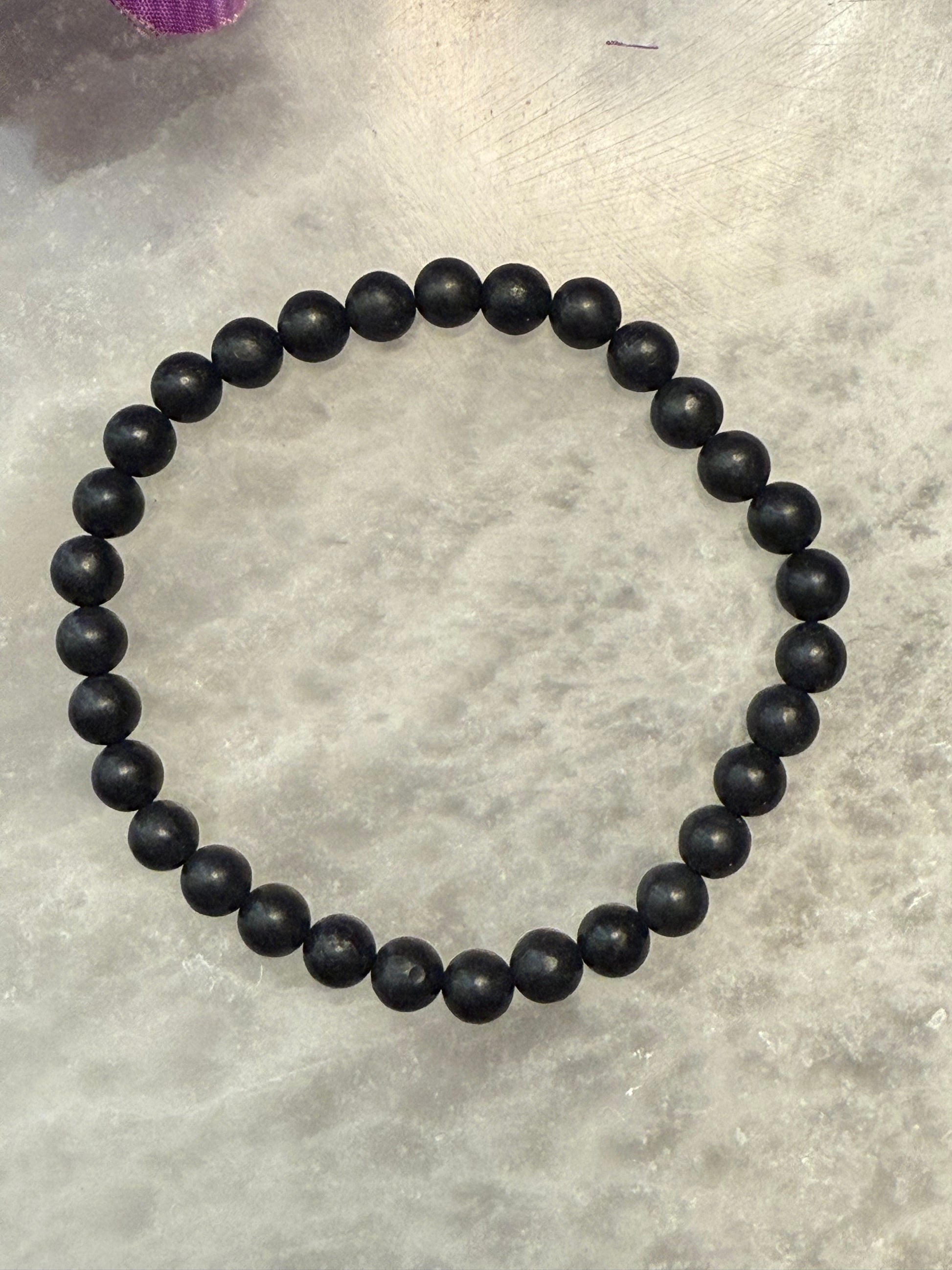 Black Natural Shungite Bead Bracelet on a gray surface