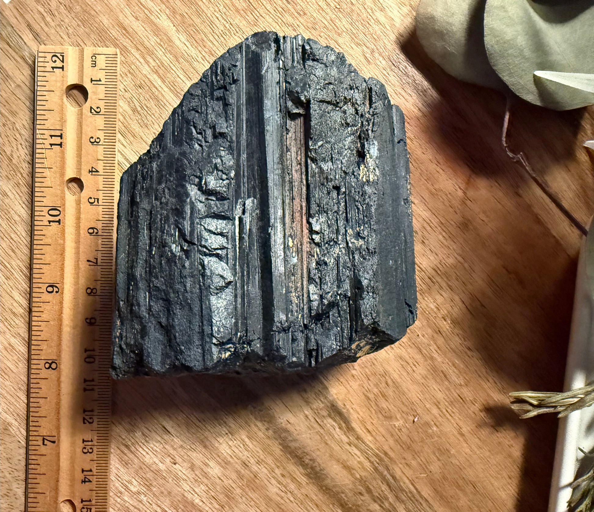 Raw Black Tourmaline on a wooden surface with a ruler for scale