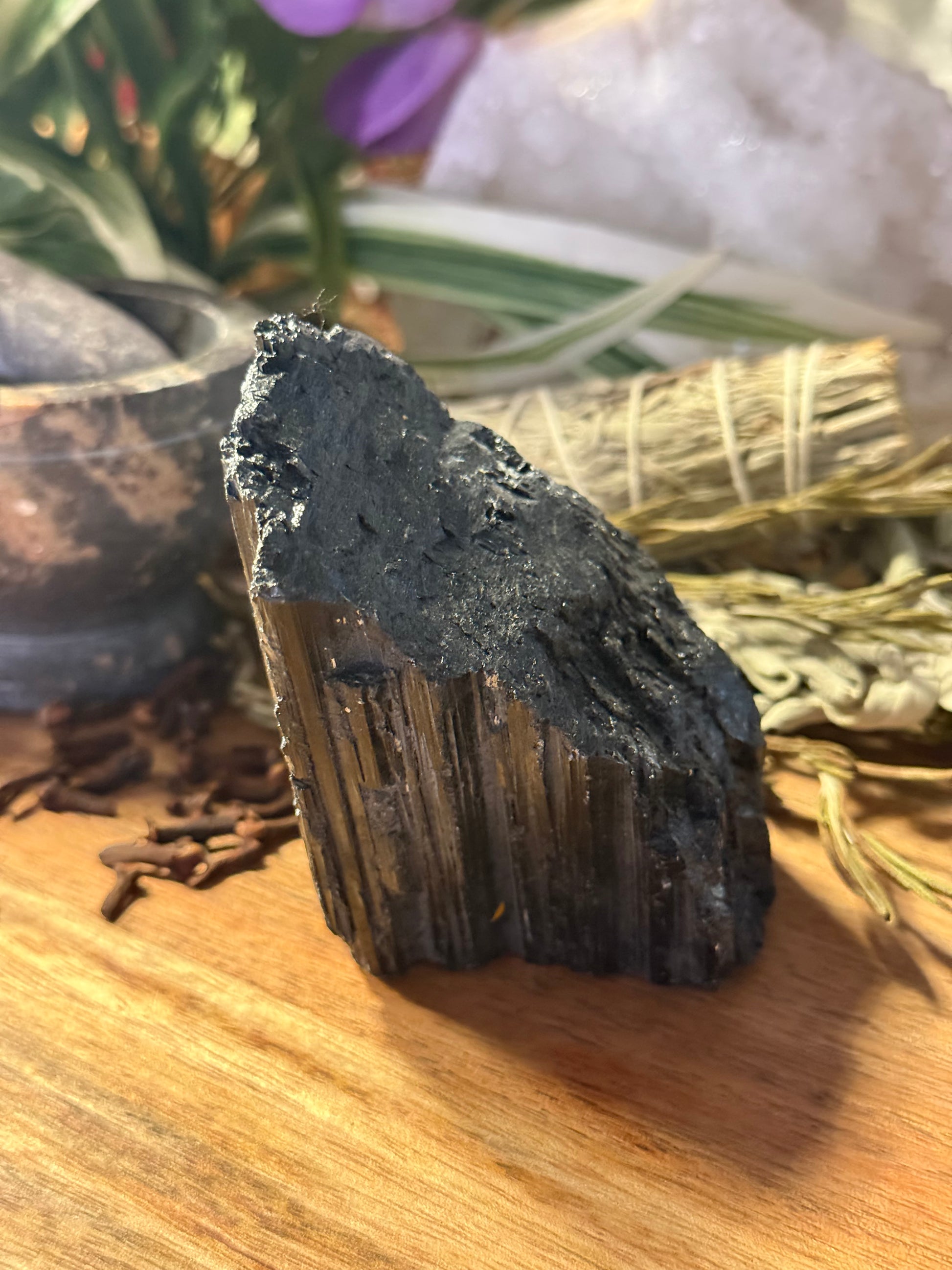 Raw Black Tourmaline on a wooden surface with blurred background