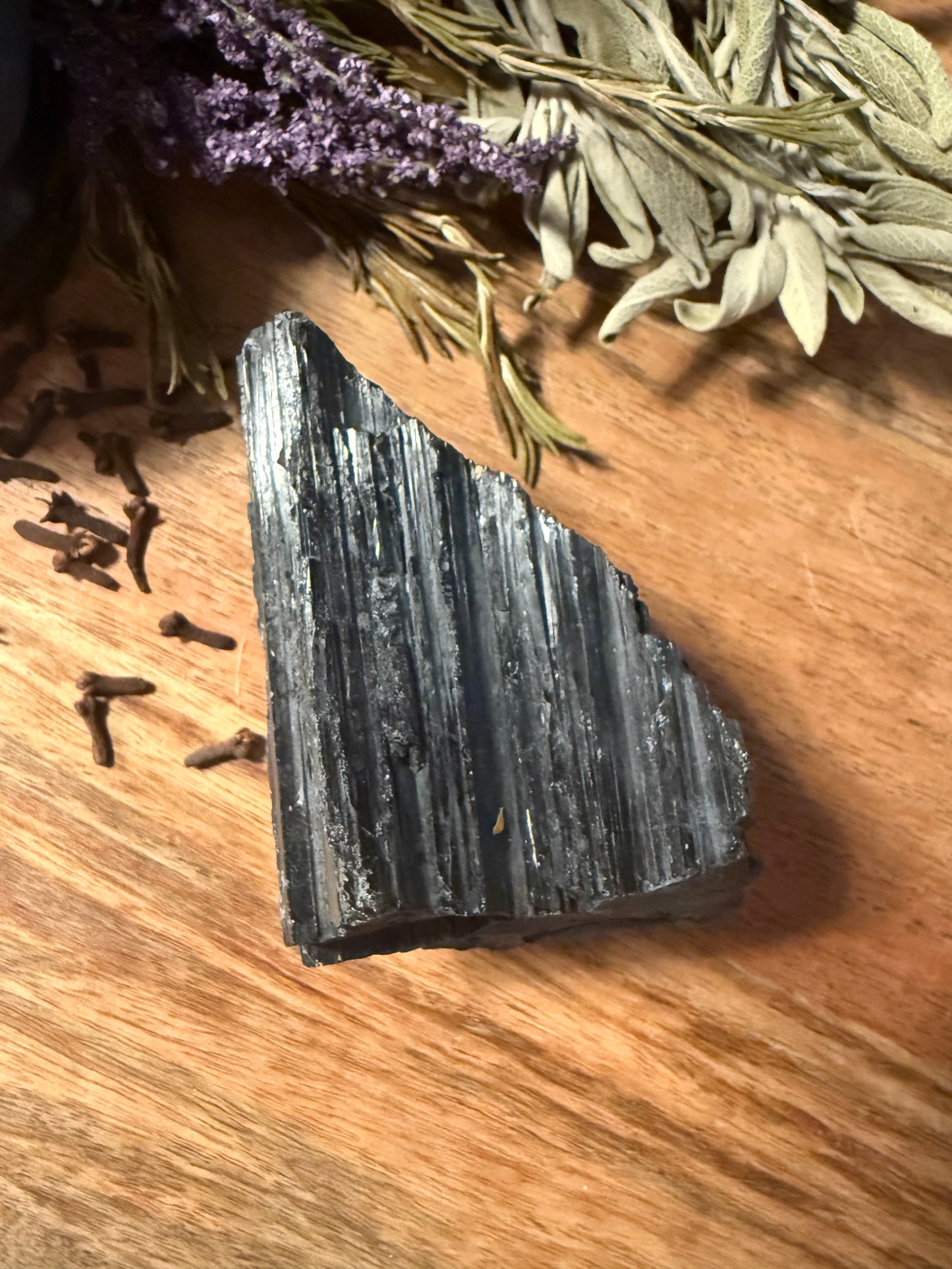 Raw Black Tourmaline on a wooden surface with herbs and spices