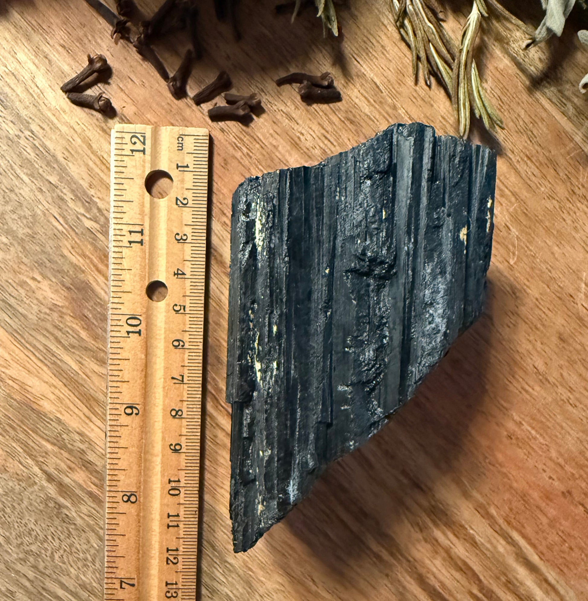 Raw Black Tourmaline with a ruler for scale on a wooden surface