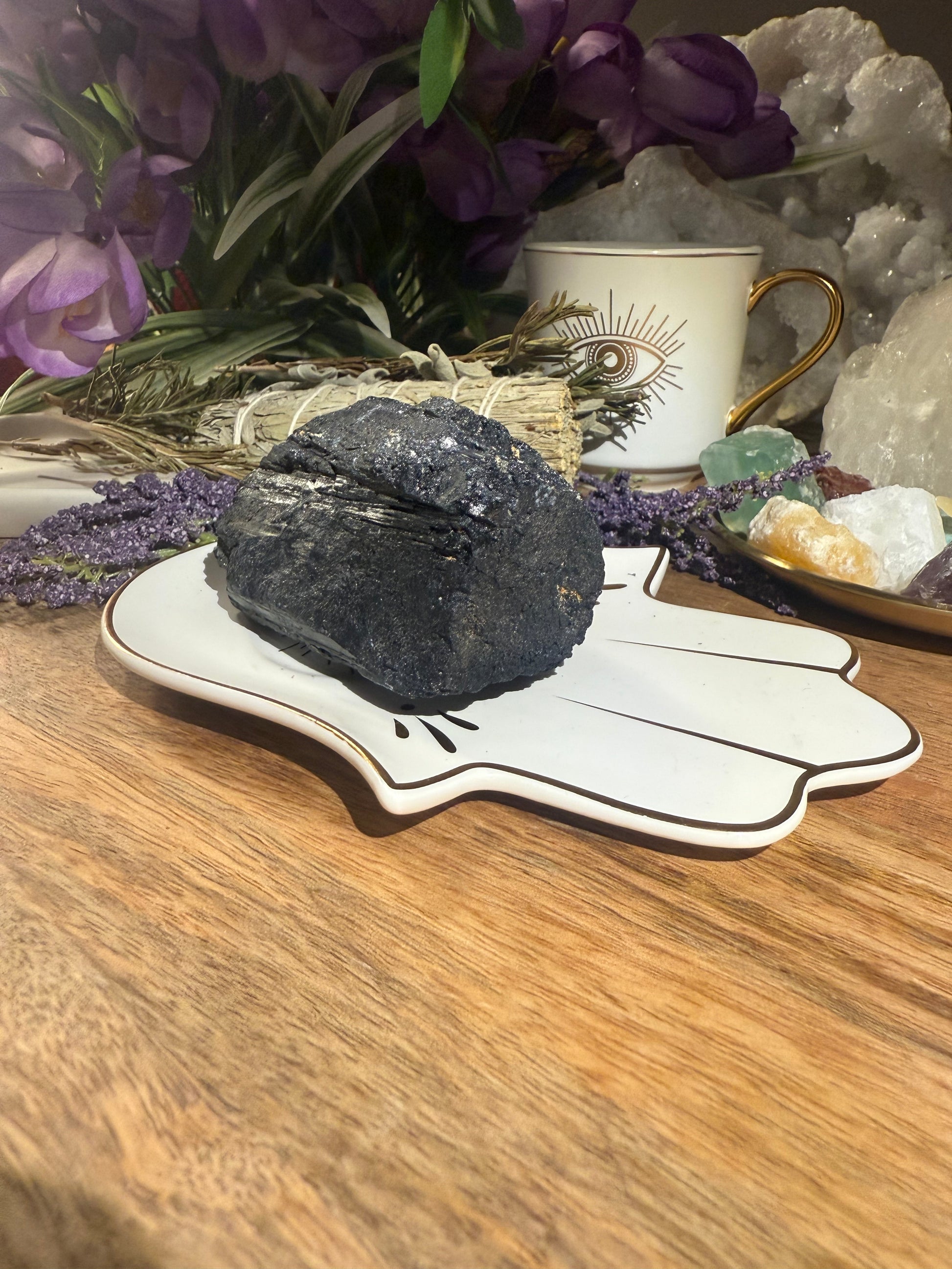 Black stone on a white dish with flowers and a cup in the background
