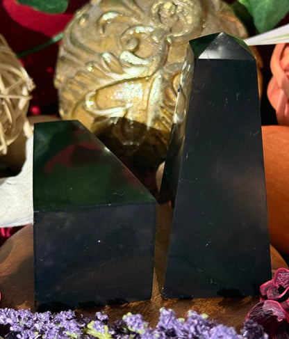 Two Shungite Pyramids on a surface with decorative elements in the background